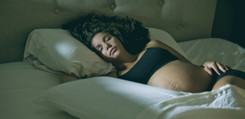 Spící těhotná žena ve spodním prádle.